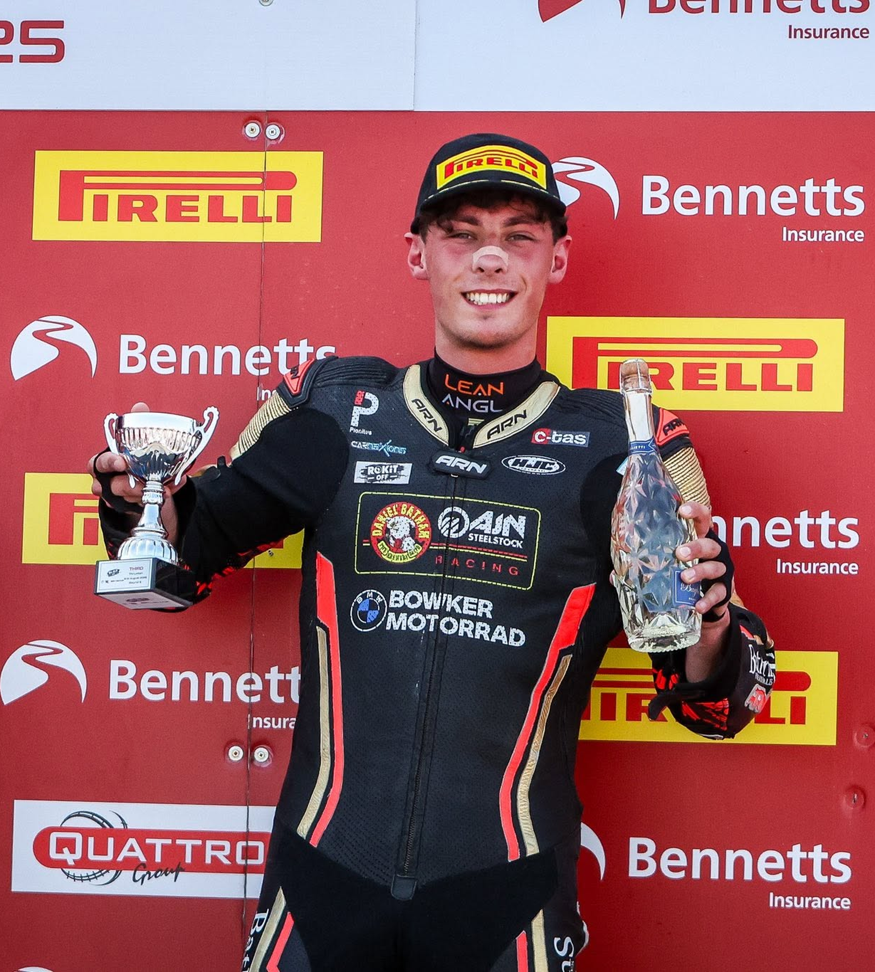 Kieran Smith holding a trophy and bottle on the Bennetts podium